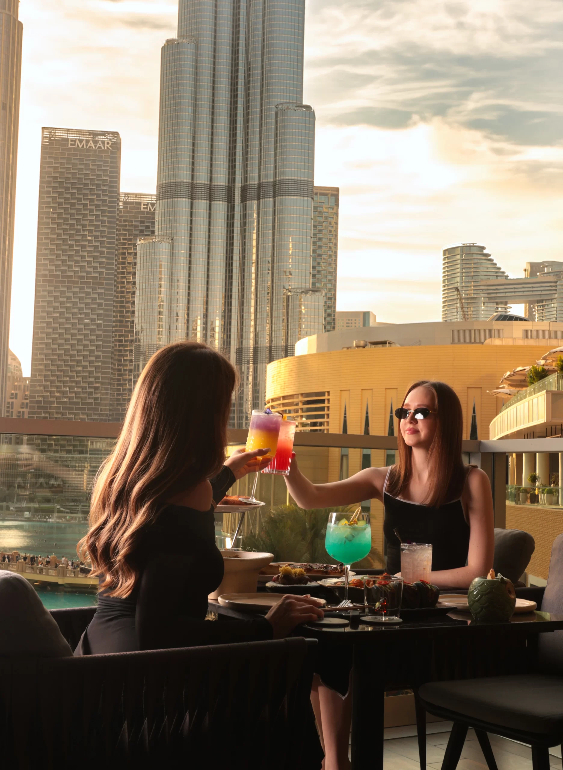 Two women enjoying drinks with Burj Khalifa in the background