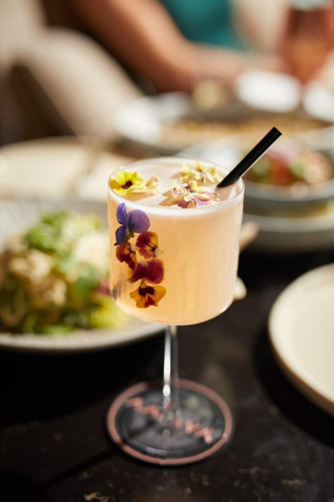 A glass of juice with petals and garnishes 