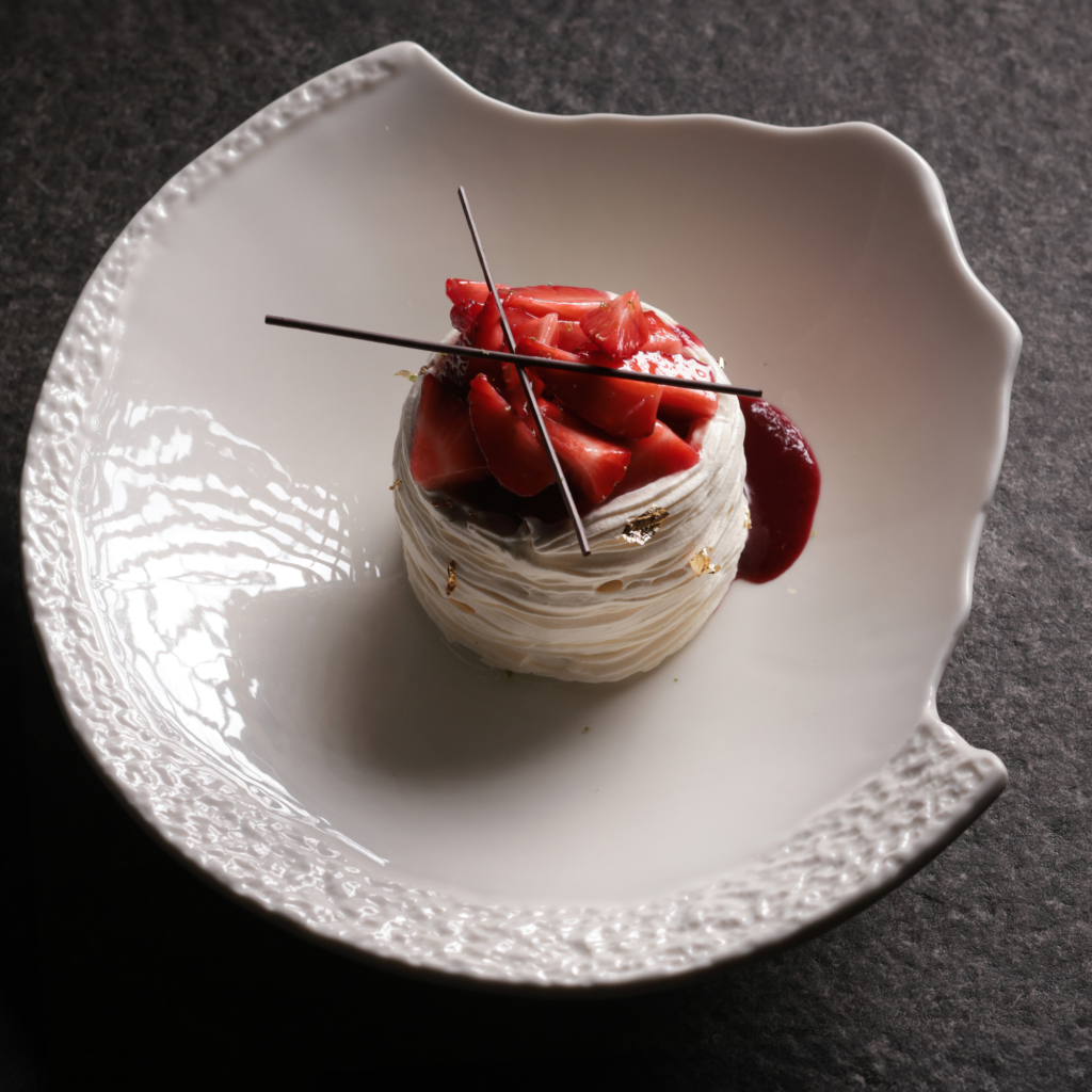 Elegant strawberry pavlova dessert topped with fresh strawberries and chocolate garnish.