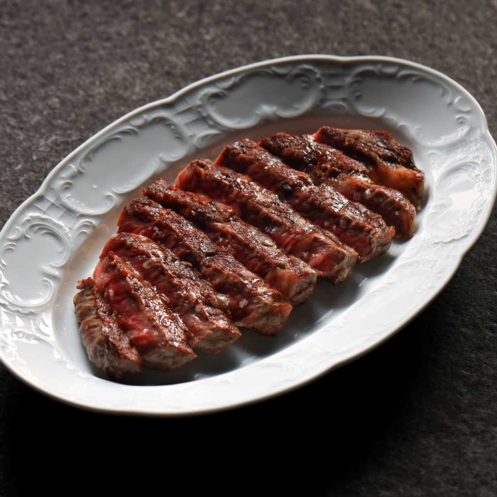 Sliced medium-rare steak served on a white decorative platter.